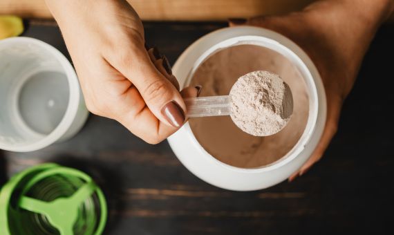 Scoop of protein powder being measured from a supplement container.