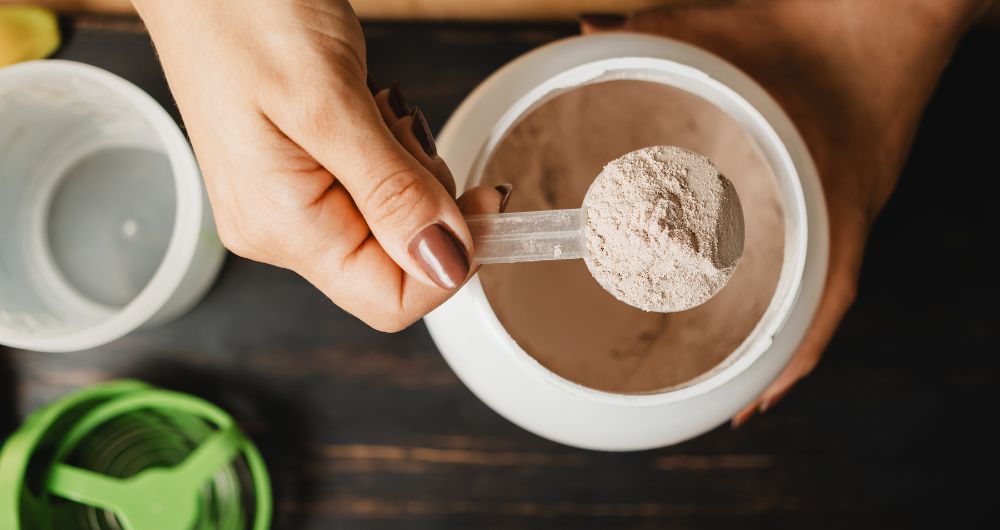 Scoop of protein powder being measured from a supplement container.