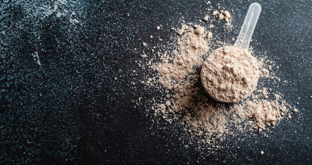 A close-up image of a spoon filled with protein powder